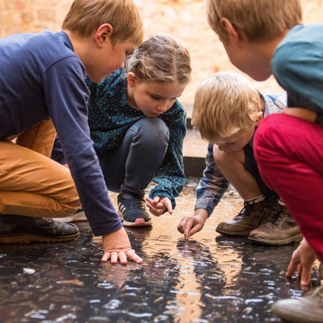 Enfant s'amusant sur l'emblème de Figeac