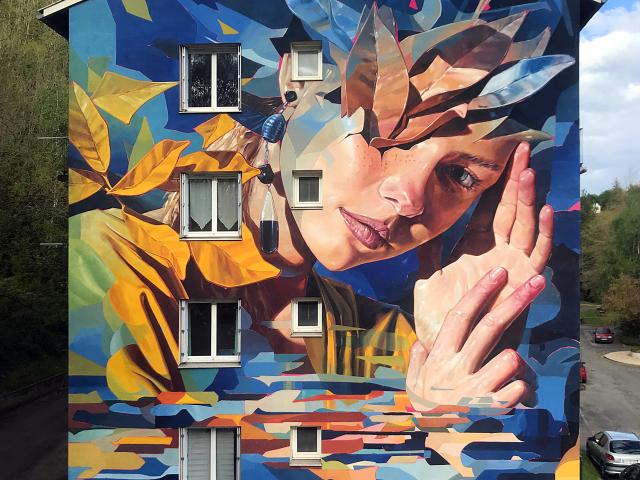 Street Art à Decazeville : un visage sur une maison.